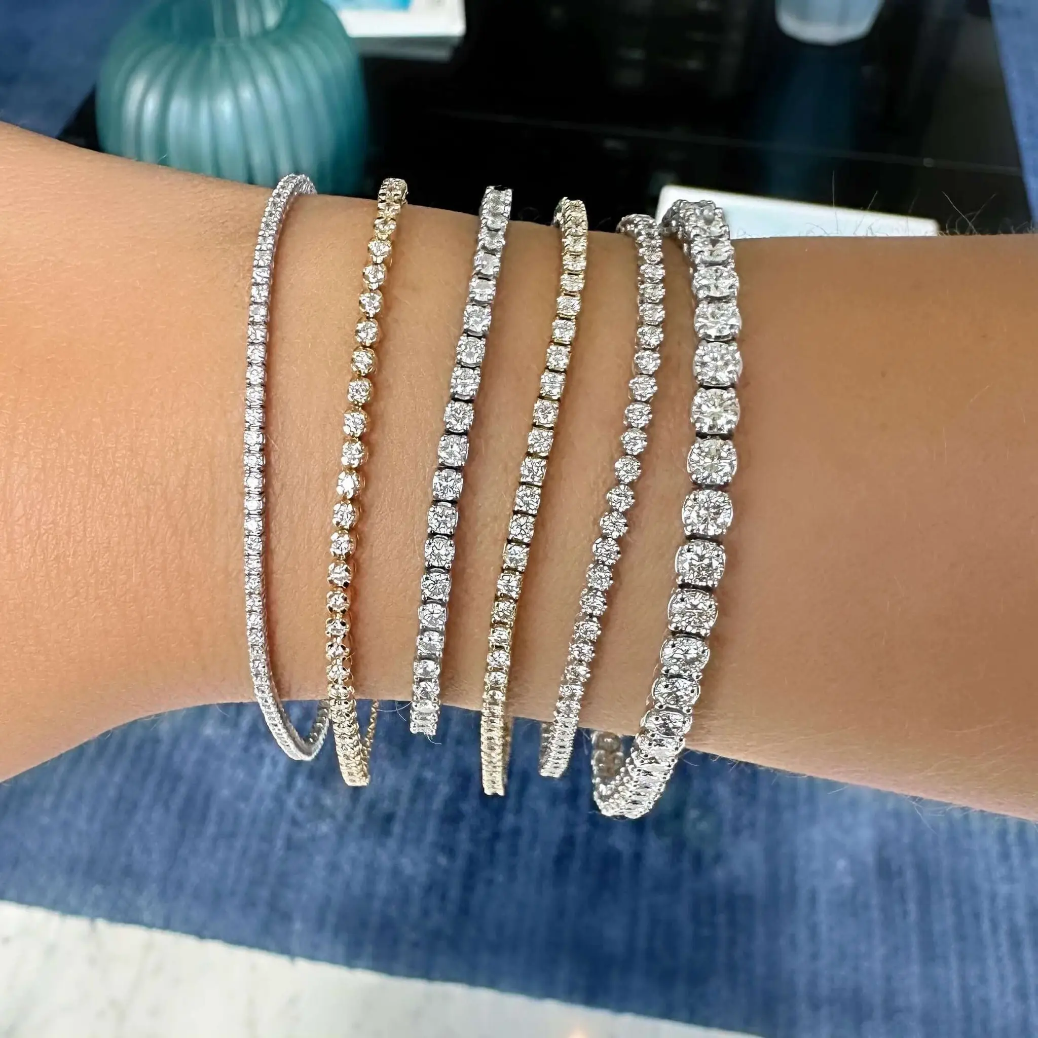 Stack of diamond tennis bracelets worn on the wrist.