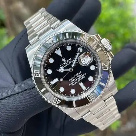 Stainless steel Rolex Submariner with a black dial held in a gloved hand.